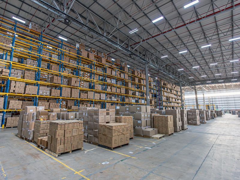 Spacious industrial warehouse featuring high-bay steel racking systems, exposed truss ceiling, and durable concrete flooring, suitable for large-scale storage and logistics operations.