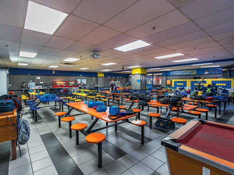 A large industrial canteen or break area featuring suspended ceilings, recessed lighting, and durable tiled flooring, designed for high-capacity staff use.