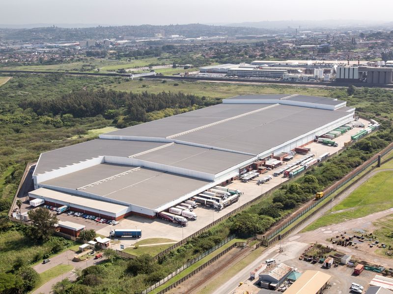 Aerial view of a large industrial warehouse facility featuring extensive loading docks, paved yard space, and secure perimeter fencing.