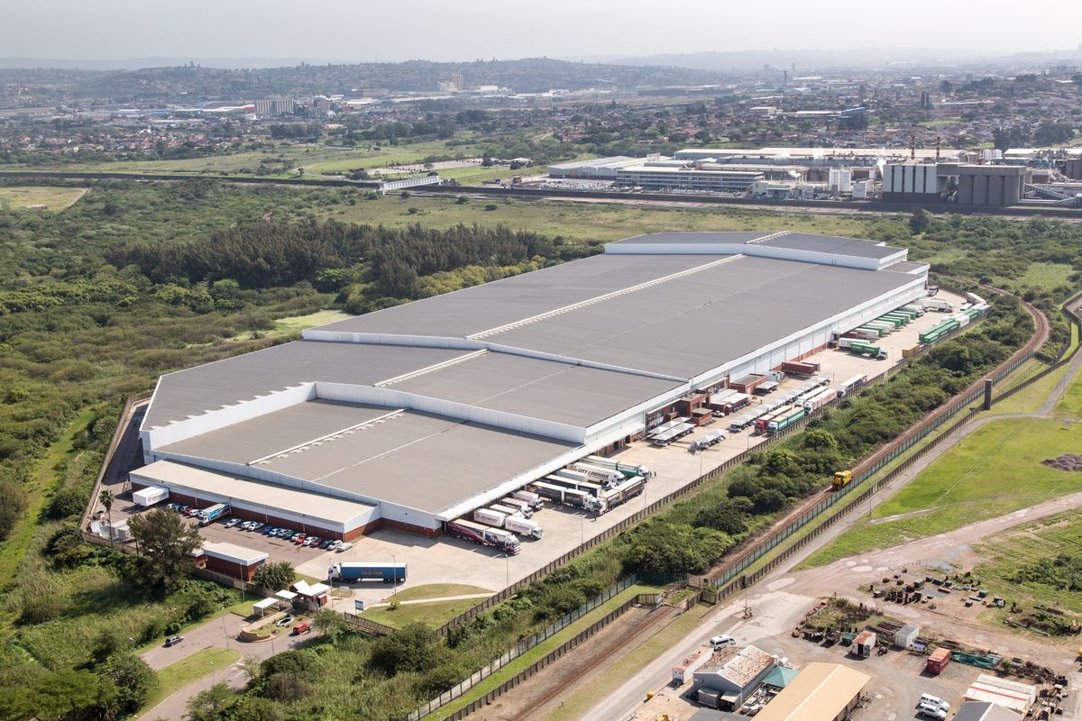 Aerial view of a large industrial warehouse facility featuring extensive loading docks, paved yard space, and secure perimeter fencing.