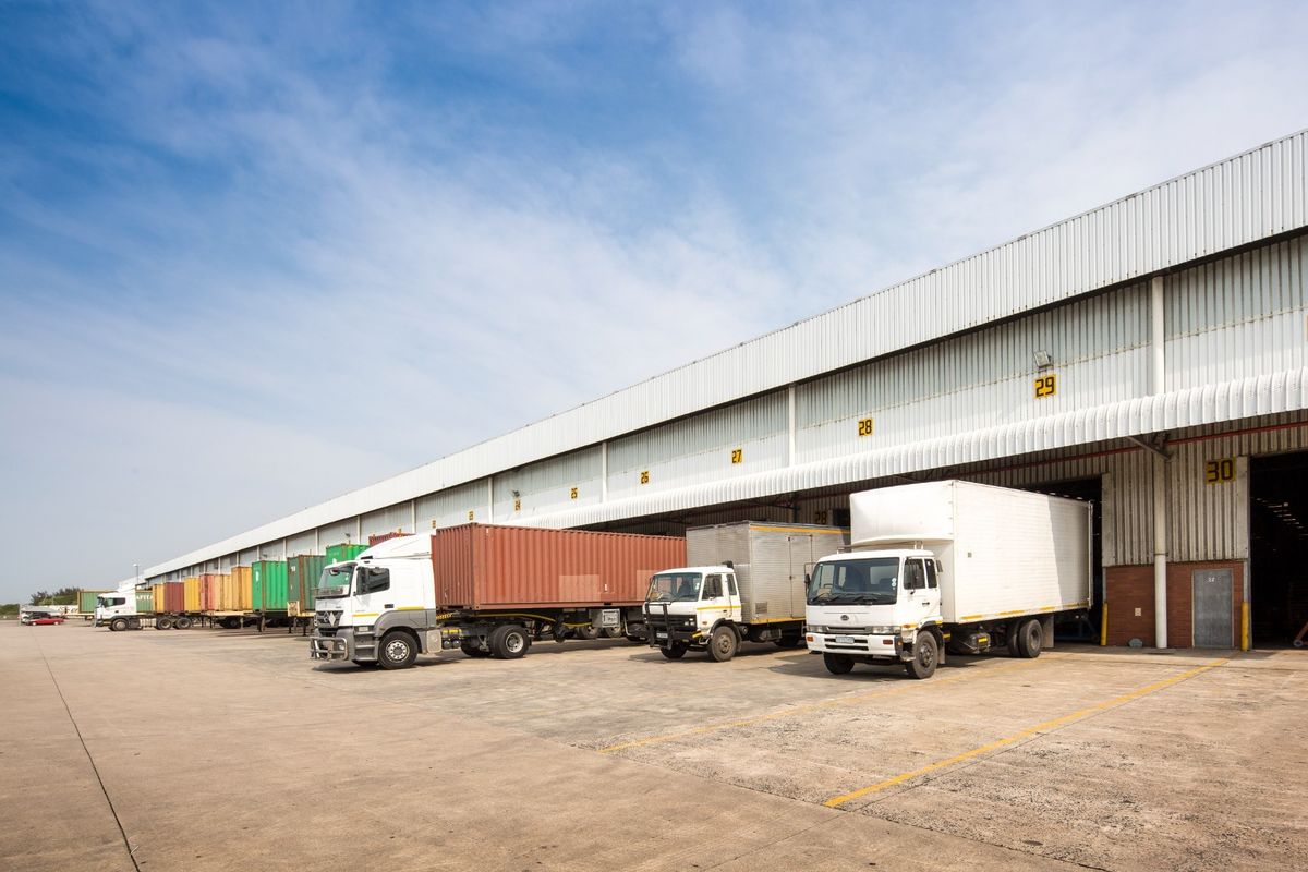 Industrial warehouse facility featuring multiple loading bays, numbered docks, and a large concrete hardstand area suitable for heavy vehicle logistics and distribution operations.