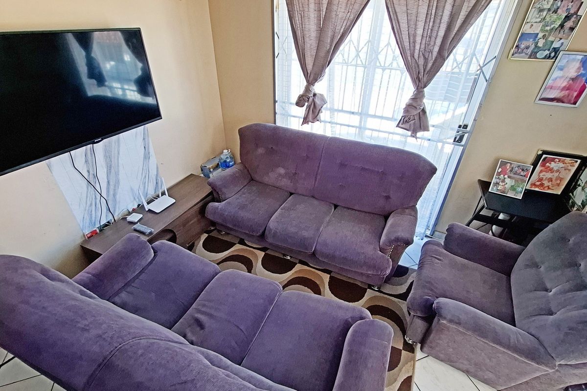 A functional living room featuring tiled flooring and a security gate, providing a comfortable and secure space for relaxation.