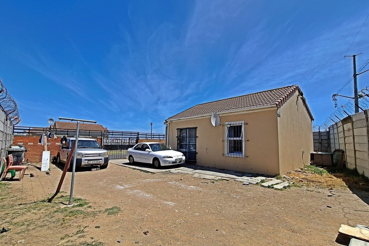 Rear exterior view of the property featuring a tiled roof, security bars on windows, and a fully enclosed yard with precast concrete boundary walls.