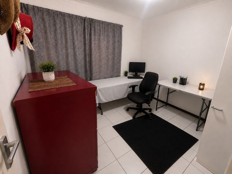 A functional home office space featuring neutral tiled flooring and clean white walls, providing a versatile area for work or study.