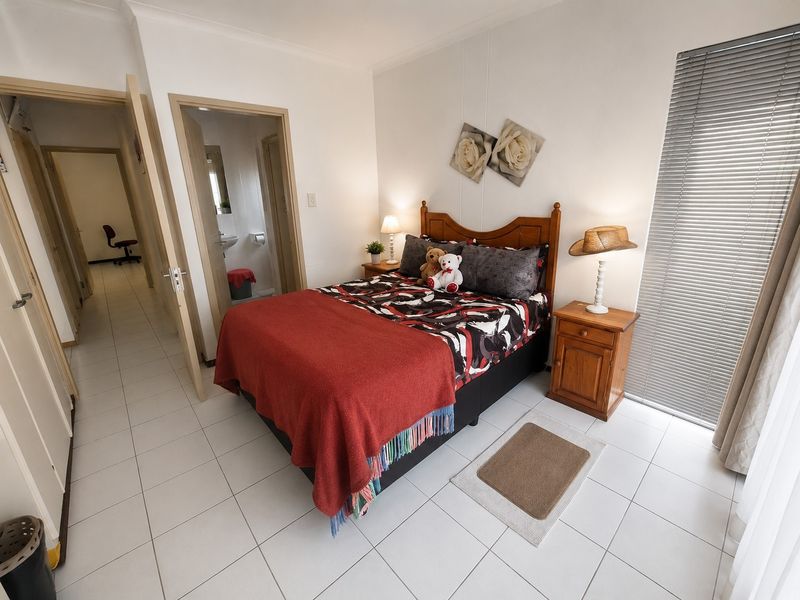 A well-lit bedroom featuring tiled flooring, venetian blinds, and direct access to an en-suite bathroom.