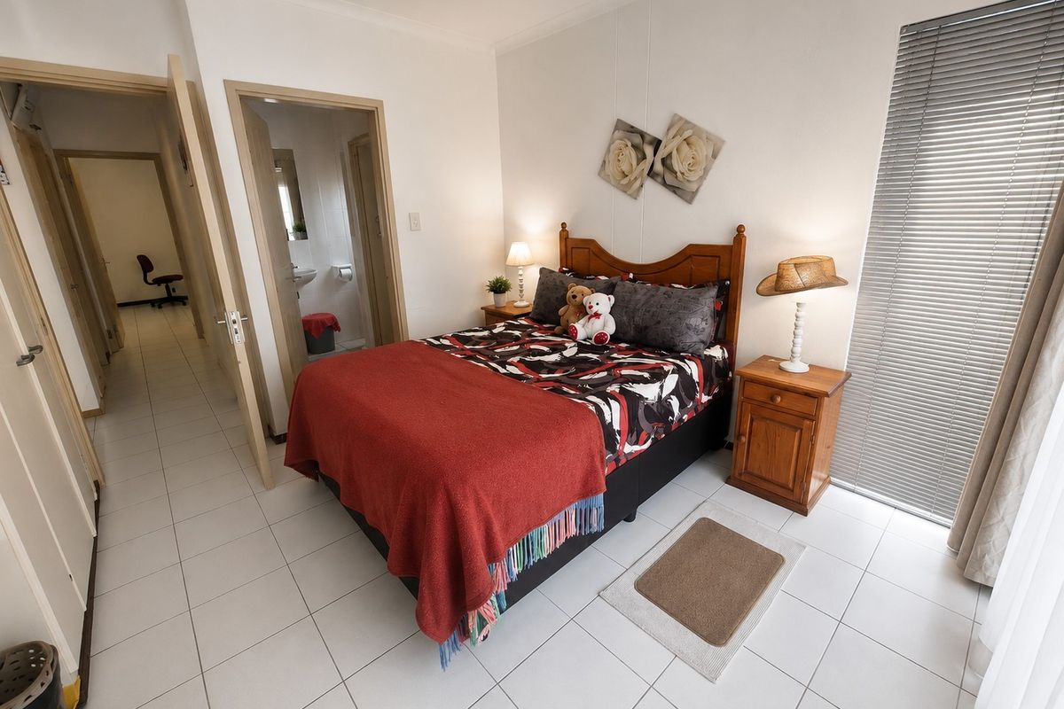 A well-lit bedroom featuring tiled flooring, venetian blinds, and direct access to an en-suite bathroom.