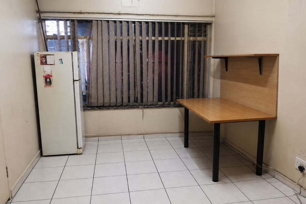 A bedroom featuring tiled flooring, built-in cupboards, and security bars on the window. The room requires cosmetic updates to the walls and finishes.