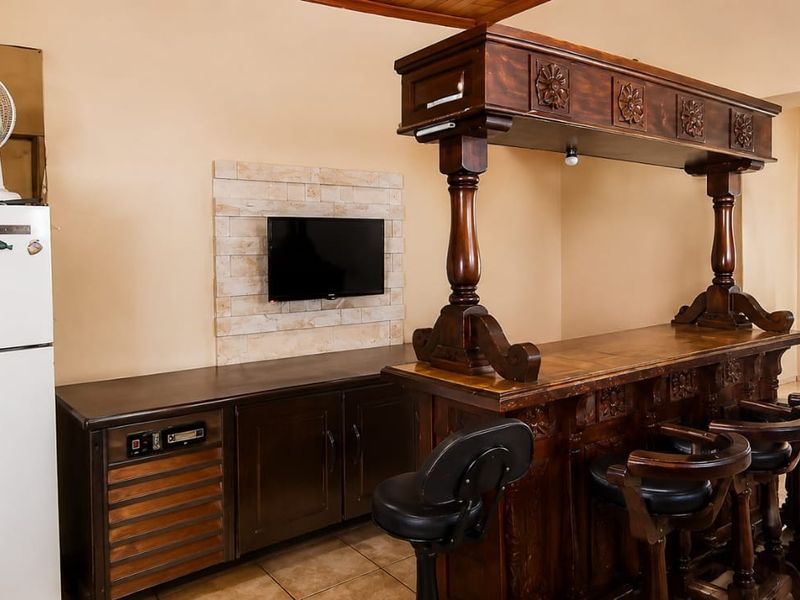 A dedicated bar area featuring a traditional wooden bar counter, stone feature wall, and tiled flooring, providing a functional space for entertainment.
