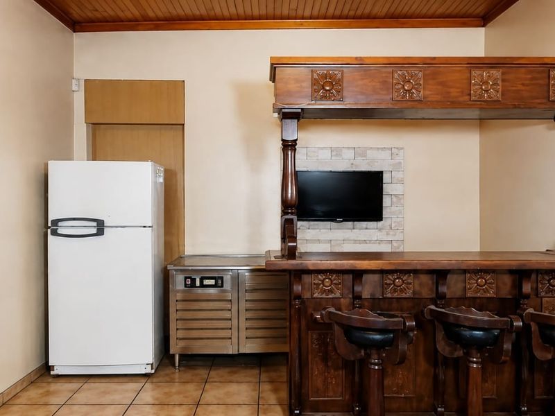 A dedicated bar area featuring a built-in wooden counter, tiled flooring, and a timber-clad ceiling, providing a classic entertainment space.