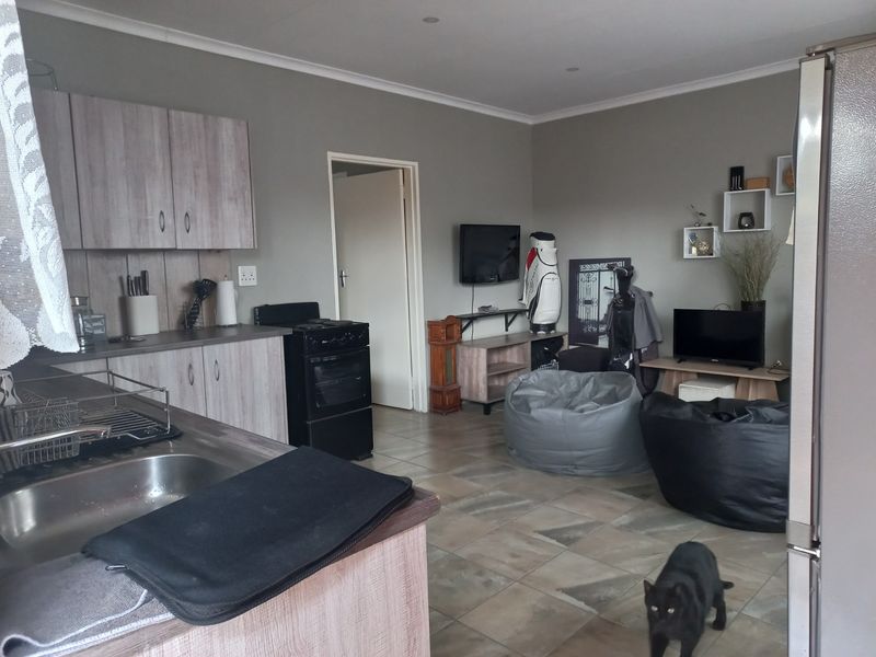Open-plan living area featuring a functional kitchen with built-in cabinetry, laminate countertops, and tiled flooring throughout the combined space.