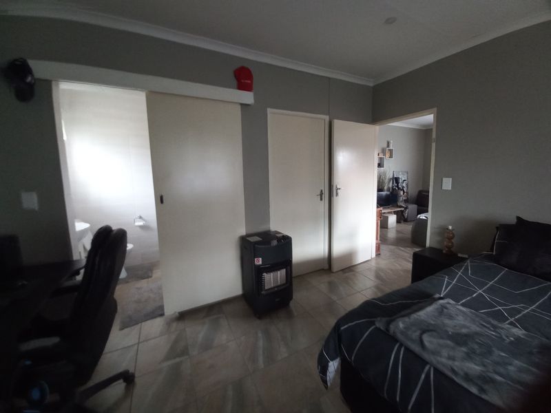 A bedroom featuring tiled flooring, coving, and direct access to an en-suite bathroom and adjacent living area.