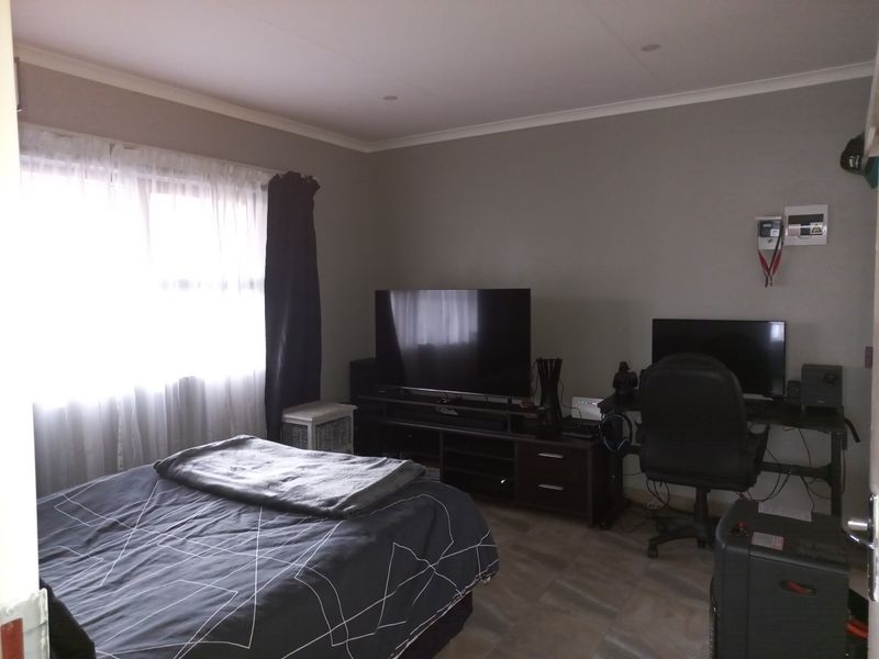 A functional bedroom featuring tiled flooring, recessed ceiling lighting, and a wall-mounted electrical distribution board.