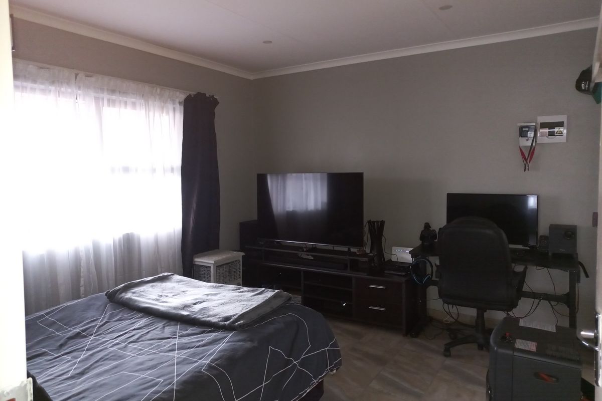 A functional bedroom featuring tiled flooring, recessed ceiling lighting, and a wall-mounted electrical distribution board.