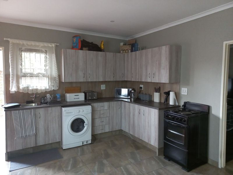 Functional kitchen featuring light wood-look cabinetry, laminate countertops, tiled flooring, and a dedicated space for a washing machine.