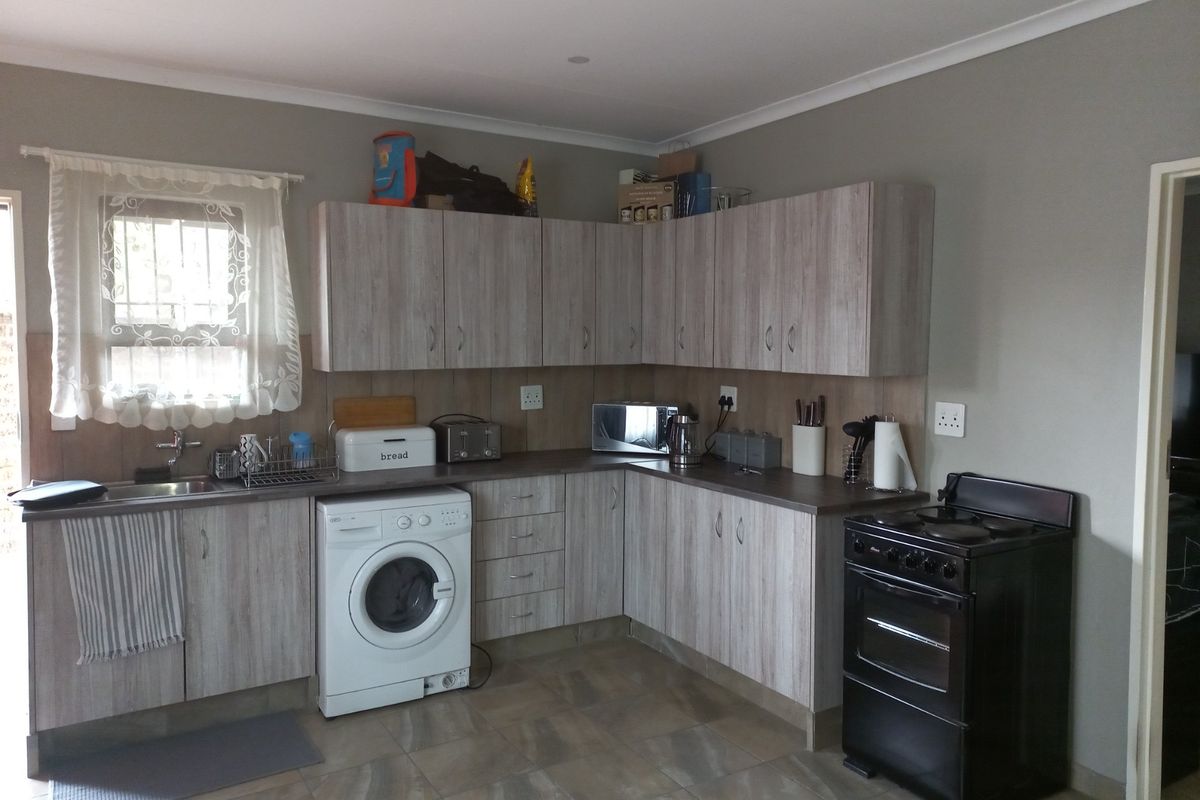 Functional kitchen featuring light wood-look cabinetry, laminate countertops, tiled flooring, and a dedicated space for a washing machine.