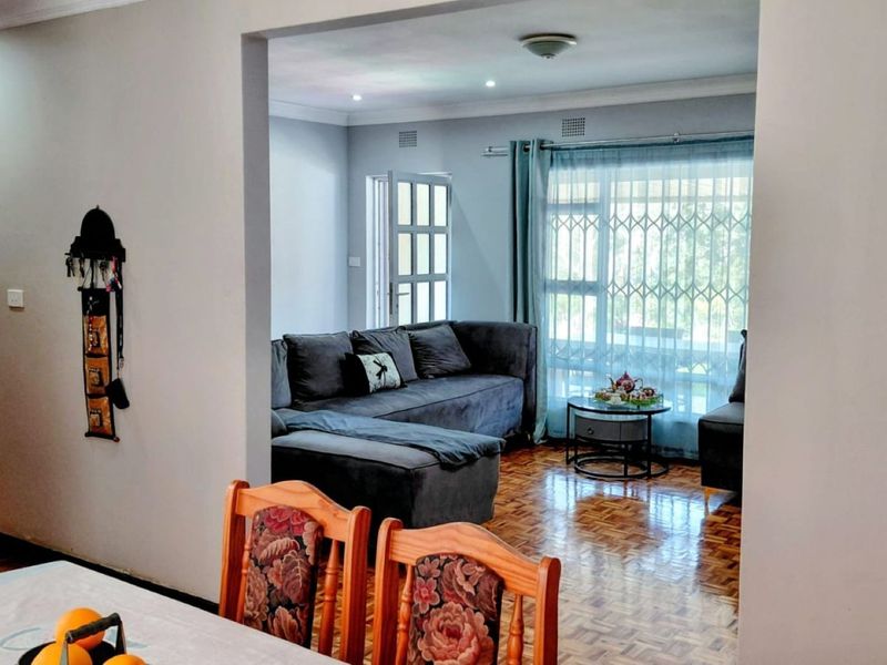 Open-plan living area featuring classic parquet flooring, a stone-clad feature wall, and direct access to the exterior through a secure sliding door.