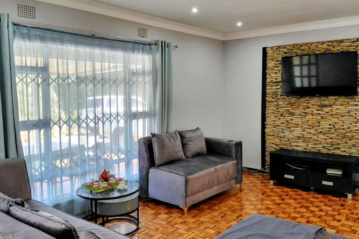 A comfortable living room featuring warm parquet flooring, a textured stone feature wall, and large sliding doors providing natural light.