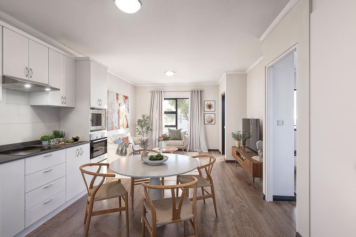 Modern open-plan living area featuring a sleek kitchen with built-in appliances, laminate flooring, and neutral finishes, creating a bright and functional retirement living space.