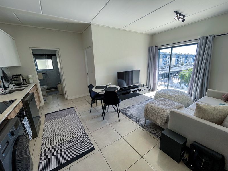 Open-plan living area featuring tiled floors, a modern kitchen, and sliding glass doors leading to a balcony with neighborhood views.