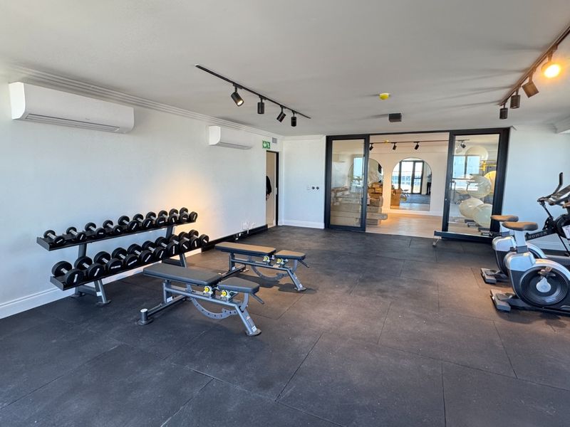 A well-maintained gym facility featuring durable rubber flooring, track lighting, and dual split-system air conditioning units for climate control.