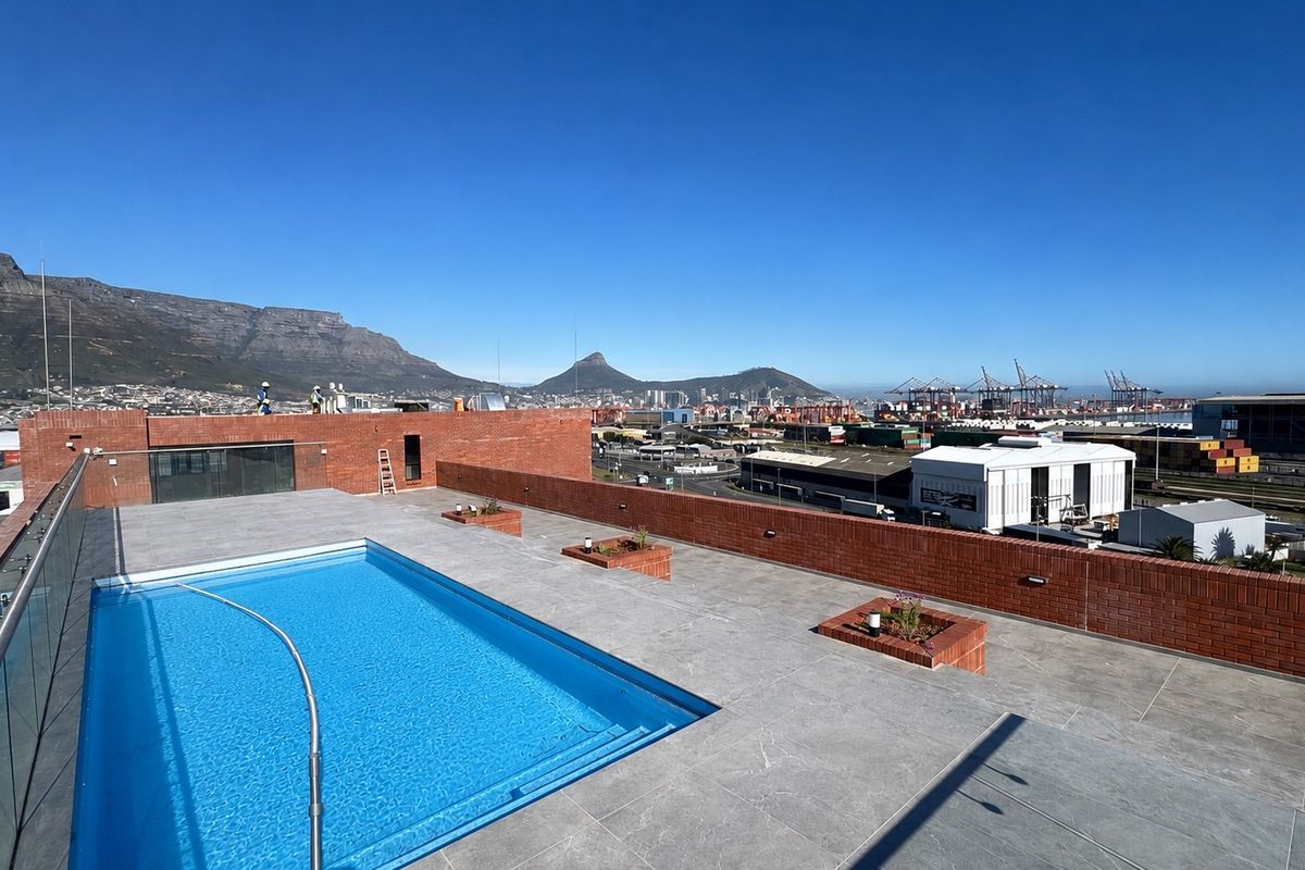Rooftop terrace featuring a swimming pool with glass balustrades, brick perimeter walls, and panoramic mountain and city views.