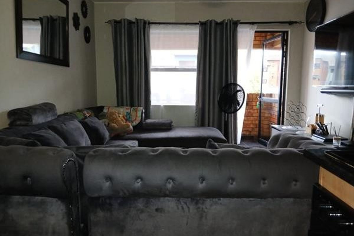 A living room area featuring a sliding glass door leading to an outdoor space, with neutral wall finishes and window treatments.