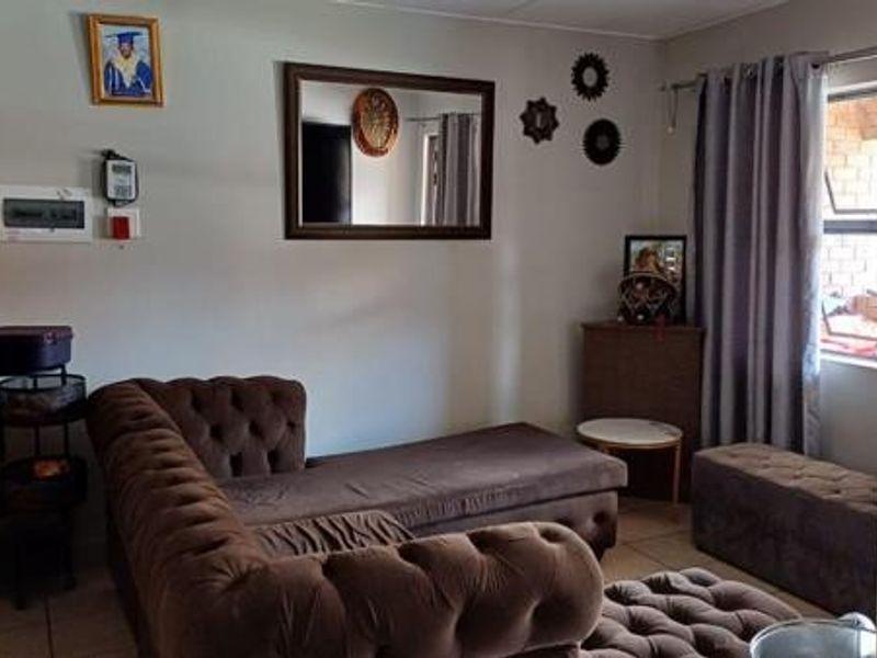 A living room area featuring tiled flooring and an exposed electrical distribution board, providing a functional space for relaxation.