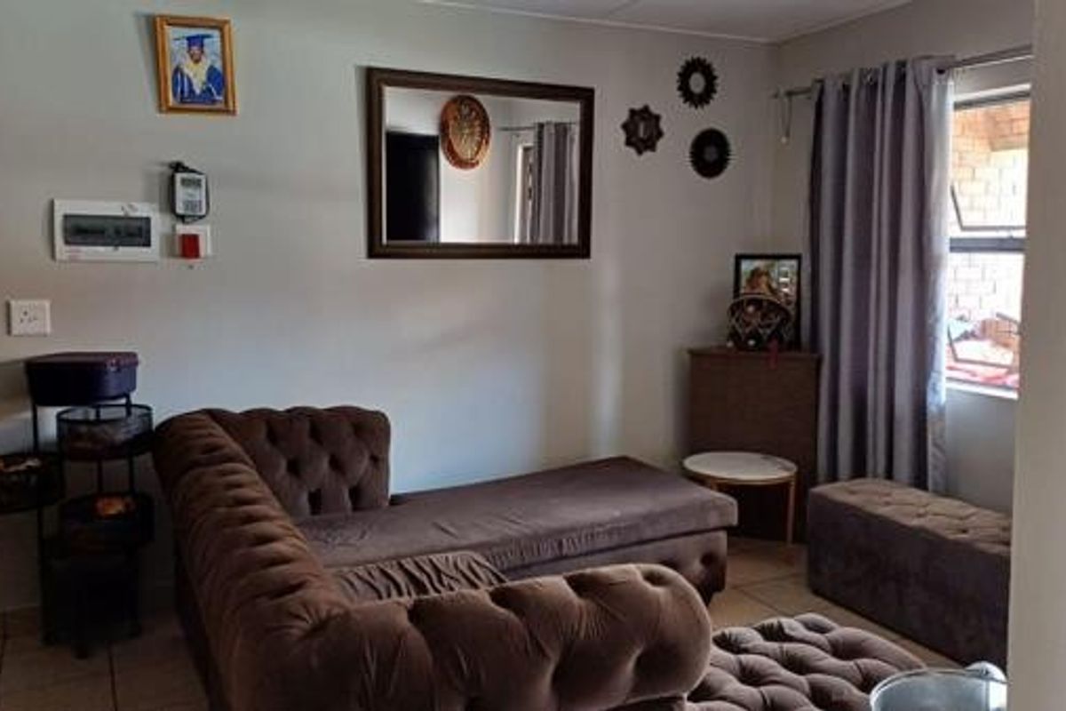 A living room area featuring tiled flooring and an exposed electrical distribution board, providing a functional space for relaxation.