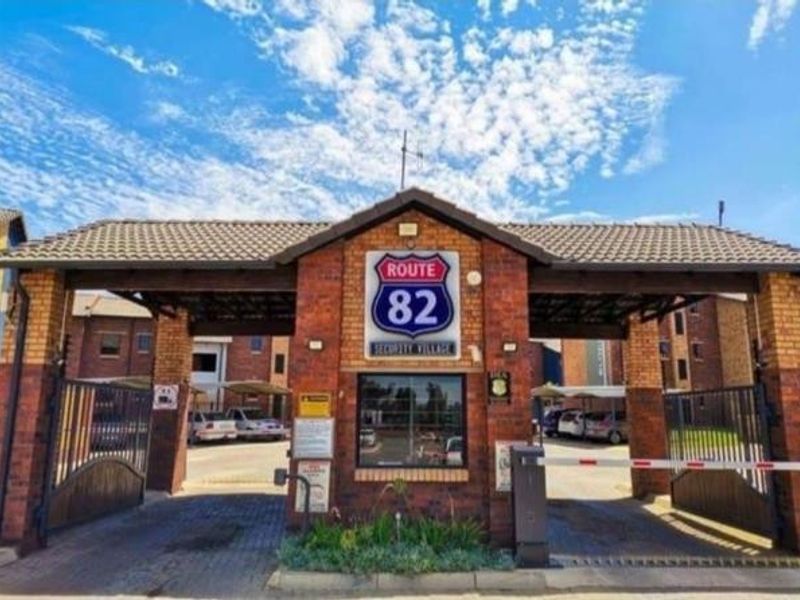 The main entrance gate to Route 82 Security Village, featuring a brick structure, security boom, and paved access point.