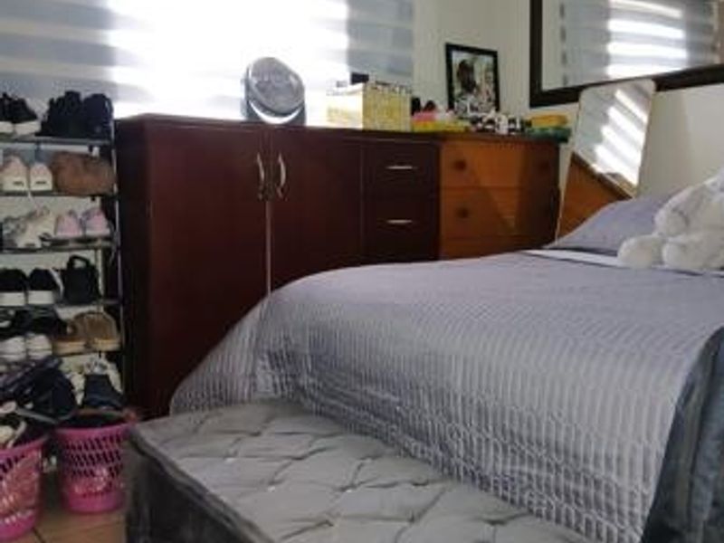 A bedroom featuring tiled flooring and window blinds, providing a functional space with potential for updated styling.