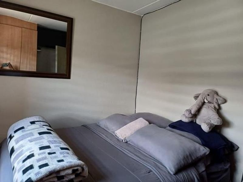 A bedroom featuring a built-in wardrobe and a wall-mounted mirror, providing functional storage and reflective space.