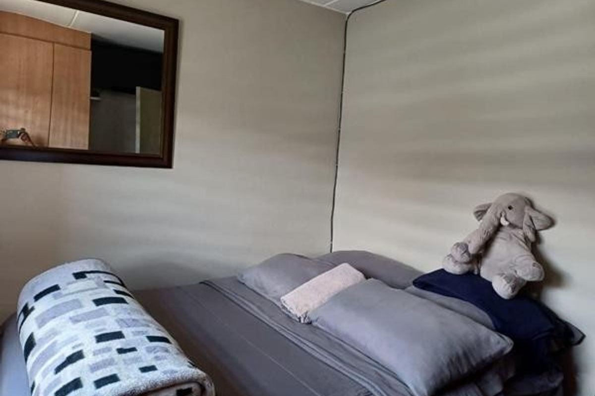 A bedroom featuring a built-in wardrobe and a wall-mounted mirror, providing functional storage and reflective space.