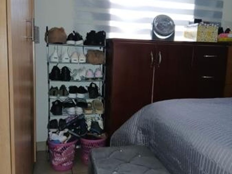 A bedroom featuring tiled flooring, a built-in wardrobe, and roller blinds, providing a functional and private living space.