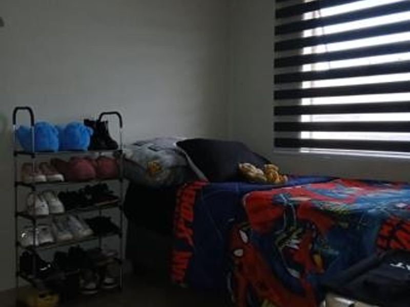 A functional bedroom featuring tiled flooring and modern zebra blinds, providing a neutral base for personalization.