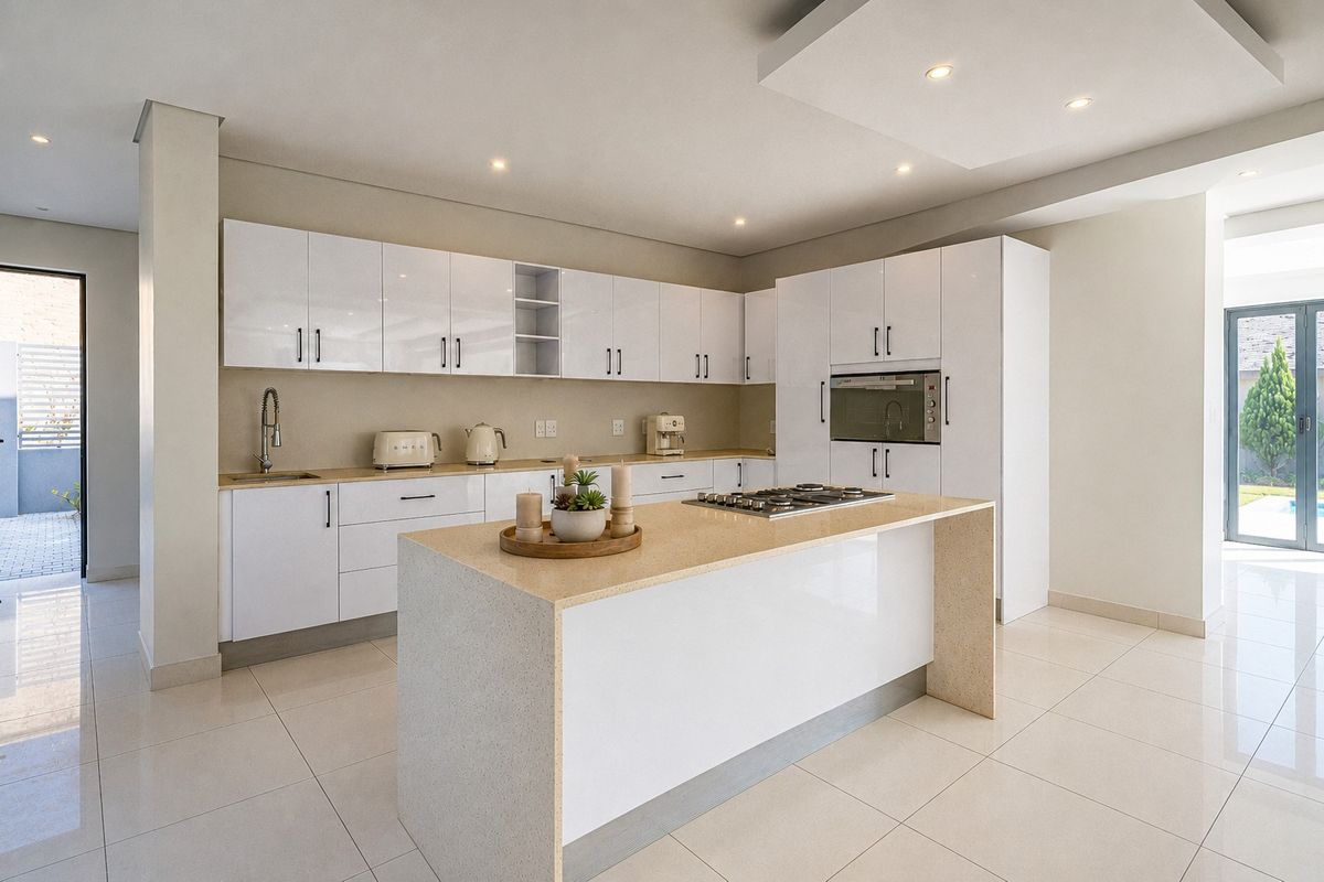 Modern kitchen featuring high-gloss white cabinetry, a central island with a gas hob, quartz countertops, and integrated appliances in a bright, open-plan space.