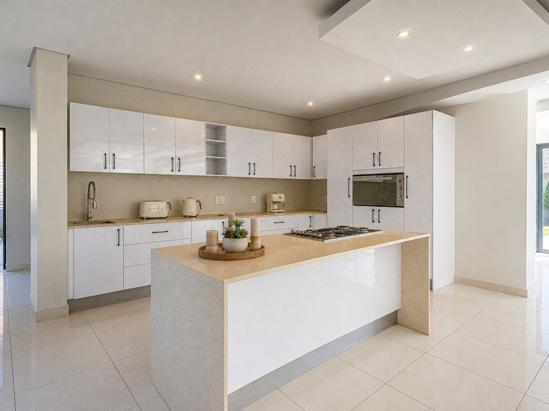 Modern kitchen featuring high-gloss white cabinetry, a central island with a gas hob, quartz countertops, and integrated appliances in a bright, open-plan space.