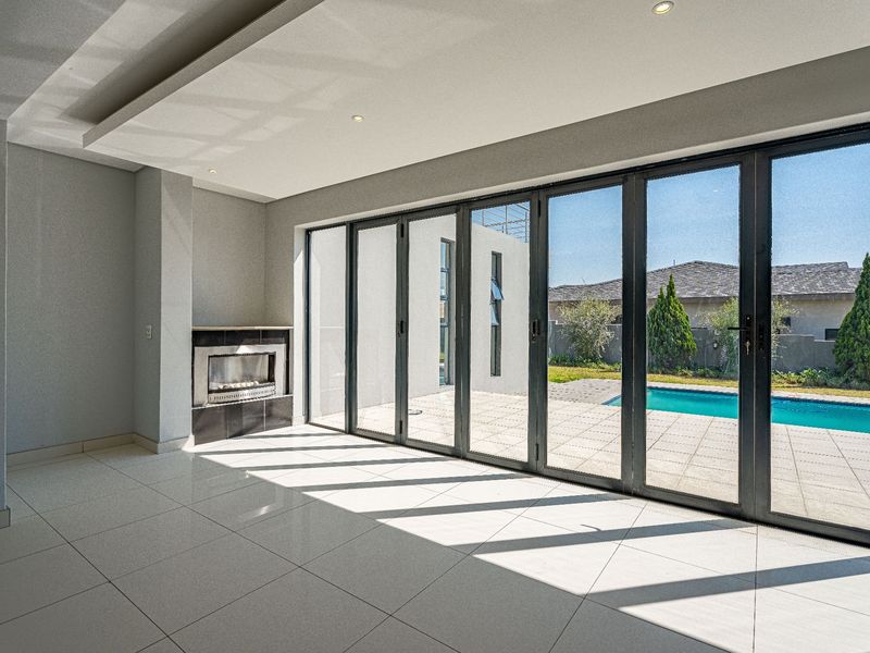 Spacious living area featuring large aluminium stacker doors opening to the pool deck, built-in fireplace, and modern tiled flooring.