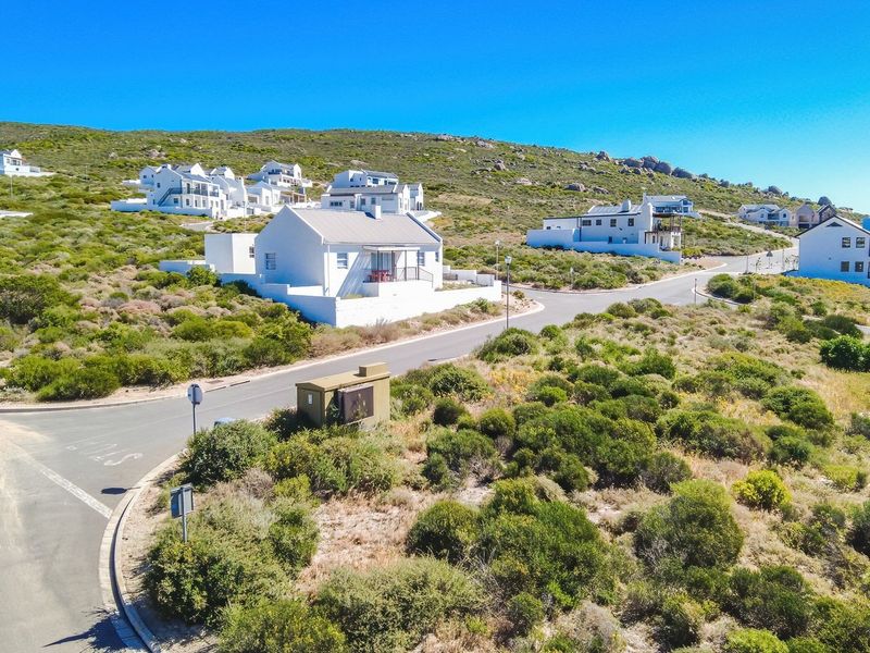 An aerial view of a residential street in a coastal estate, showcasing the surrounding landscape and nearby properties.