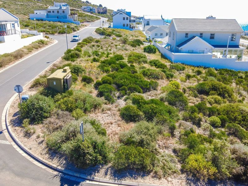 An aerial view of a vacant residential plot situated on a corner lot within a developed coastal neighborhood.