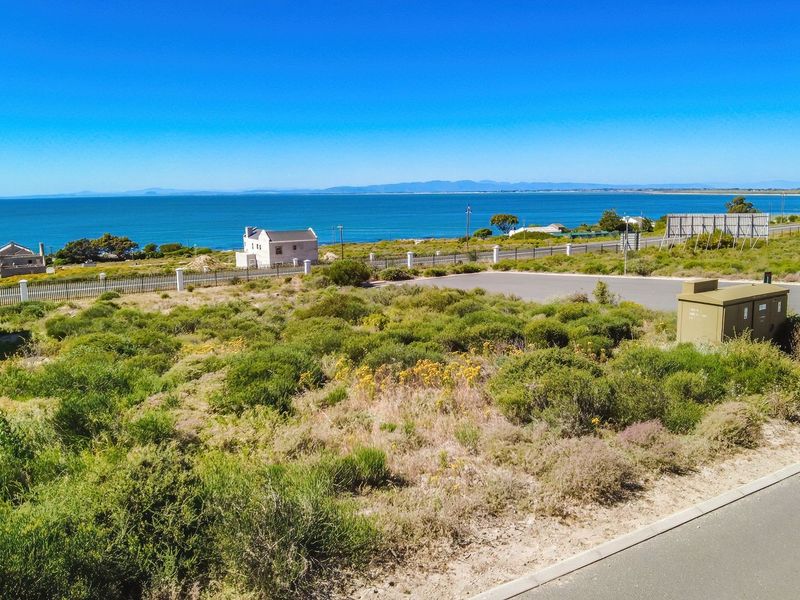 A scenic view overlooking a vacant residential plot with coastal landscape and ocean views in the background.