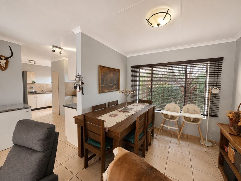 Open plan dining area featuring tiled flooring and natural light, with a view through to the functional kitchen space.
