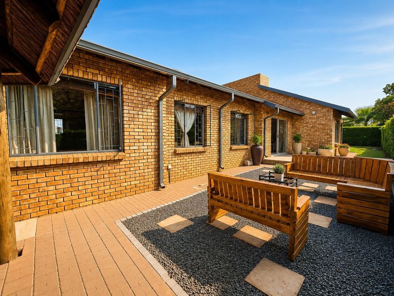 A well-maintained rear exterior featuring a face brick facade, paved patio area, and gravel landscaping with integrated stepping stones.