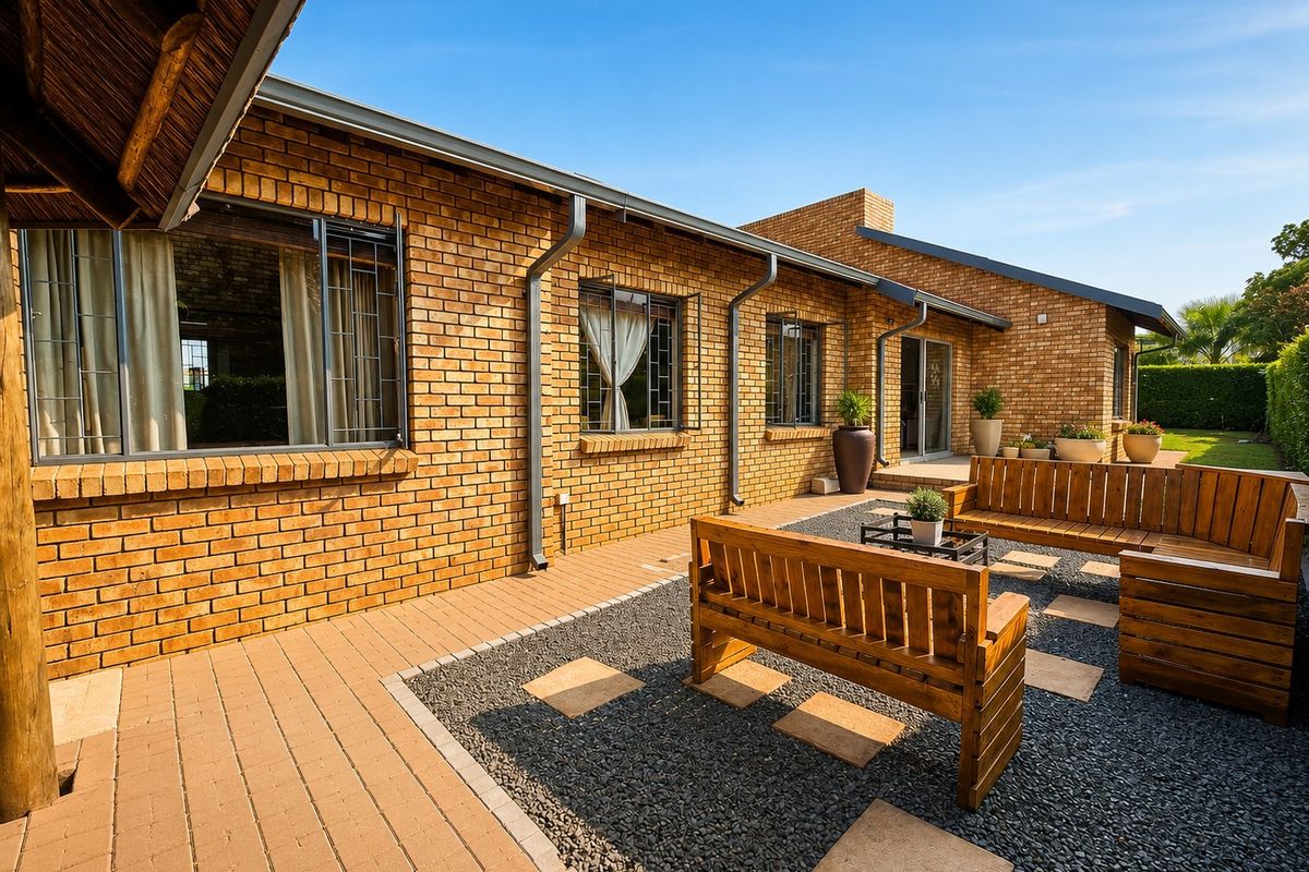 A well-maintained rear exterior featuring a face brick facade, paved patio area, and gravel landscaping with integrated stepping stones.