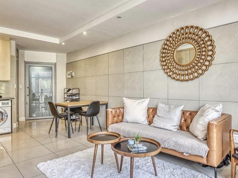 Modern open-plan living area featuring large format wall tiles, sleek floor tiling, and recessed ceiling lighting, creating a bright and contemporary living space.