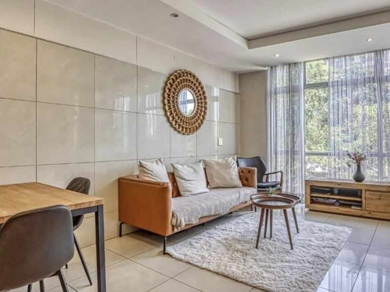 A bright and modern living area featuring large floor-to-ceiling windows, polished porcelain floor tiles, and a contemporary tiled feature wall.