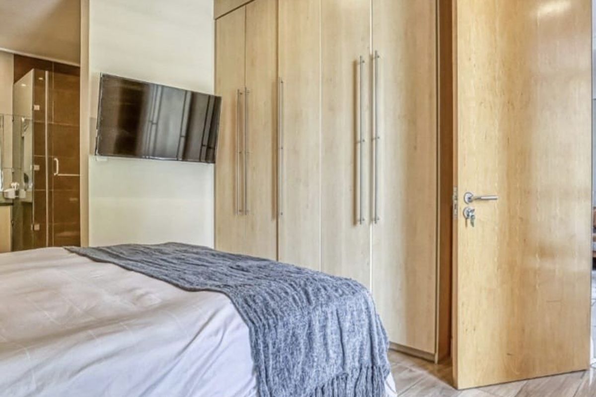 Modern bedroom featuring light wood built-in cupboards, tiled flooring, and direct access to an en-suite bathroom.