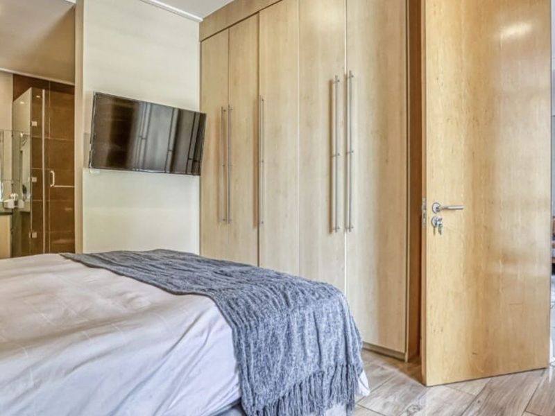 Modern bedroom featuring light wood built-in cupboards, tiled flooring, and direct access to an en-suite bathroom.
