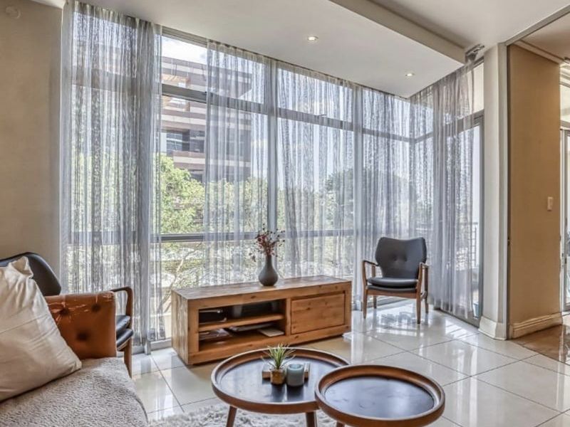 A bright living room featuring large floor-to-ceiling windows, polished tiled flooring, and a modern bulkhead ceiling with recessed lighting.