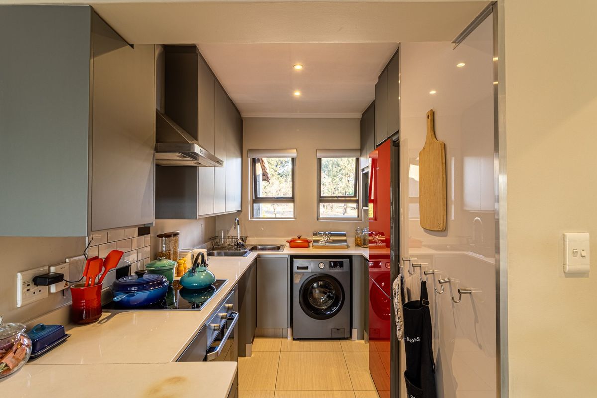 Modern galley-style kitchen featuring sleek grey cabinetry, quartz countertops, integrated appliances, and a clean subway tile backsplash with efficient recessed lighting.