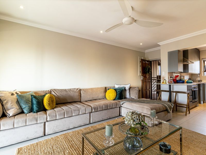Open-plan living area featuring tiled floors, recessed lighting, a ceiling fan, and a modern kitchen with built-in cabinetry and a breakfast bar.